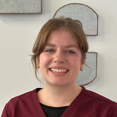 Ruth Kneebone smiling in maroon scrubs.
